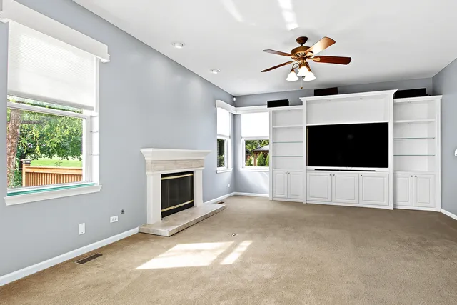 a view of a livingroom with a flat screen tv ceiling fan and window