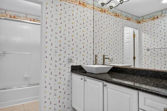 a bathroom with a granite countertop sink a mirror and a bathtub