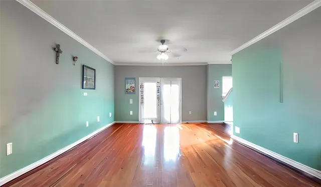 a view of an empty room with window and wooden floor