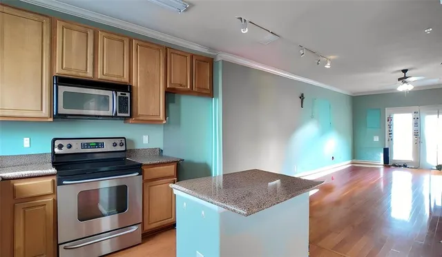 a kitchen with stainless steel appliances granite countertop a stove a microwave oven cabinets and a wooden floor