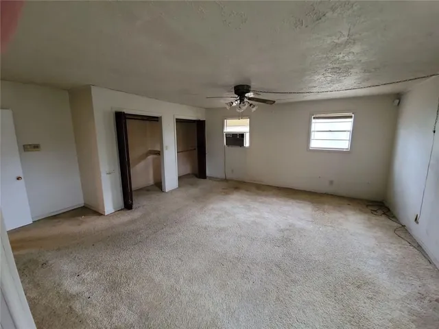 an empty room with windows and ceiling fan