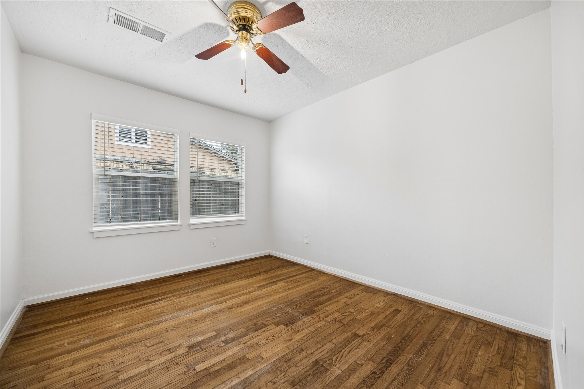 7515 Magnolia Street Houston, TX 77023 - Photo 11 of 16 The 9×11 third bedroom features hardwood flooring, a large window that provides plenty of natural light, a walk-in closet, and a ceiling fan with light—offering a comfortable and versatile secondary space.