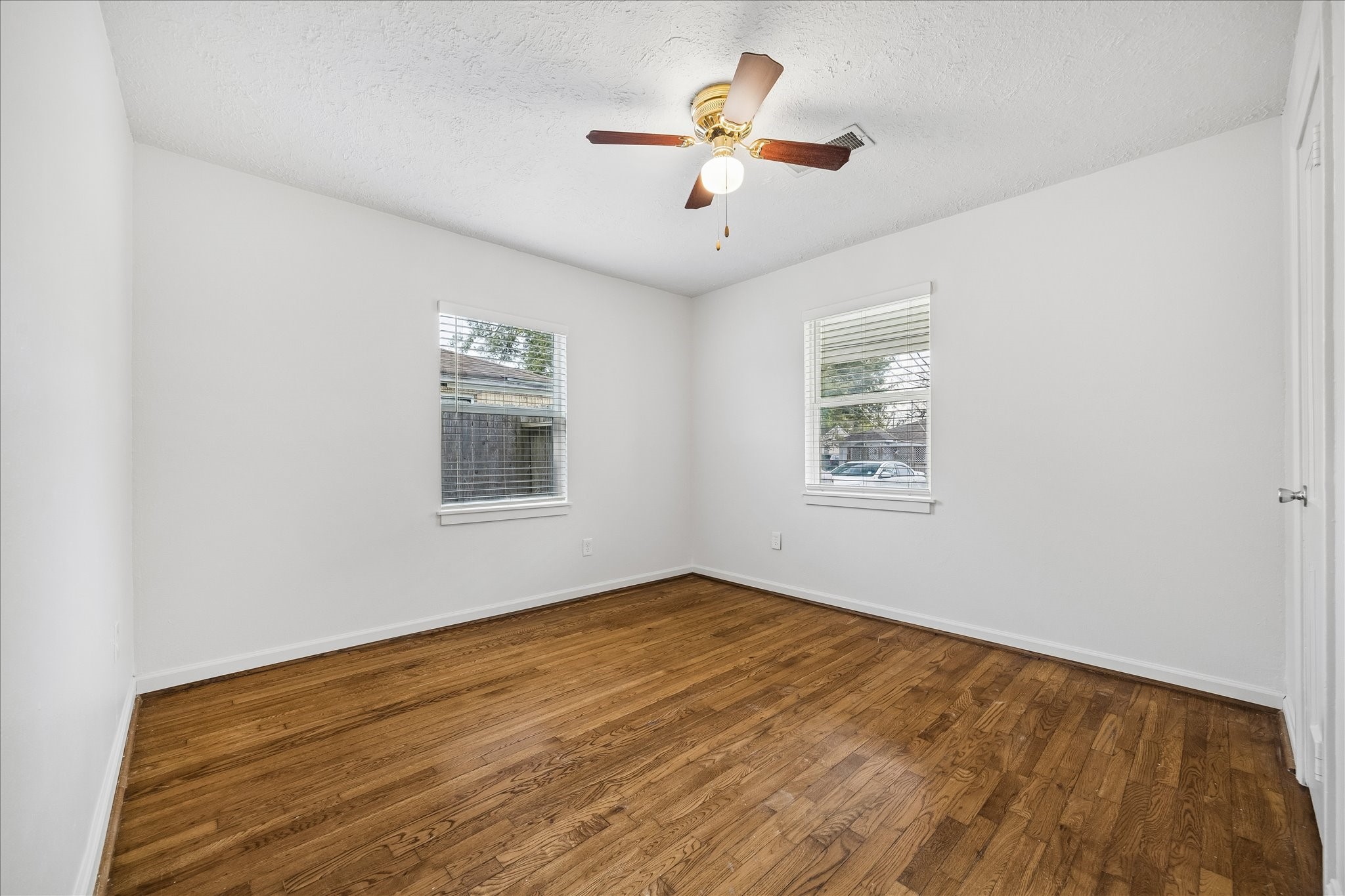 7515 Magnolia Street Houston, TX 77023 - Photo 12 of 16 The 11×11 fourth bedroom features hardwood flooring, a generous window that fills the space with natural light, a walk-in closet, and a ceiling fan with light—creating a bright and comfortable secondary bedroom.