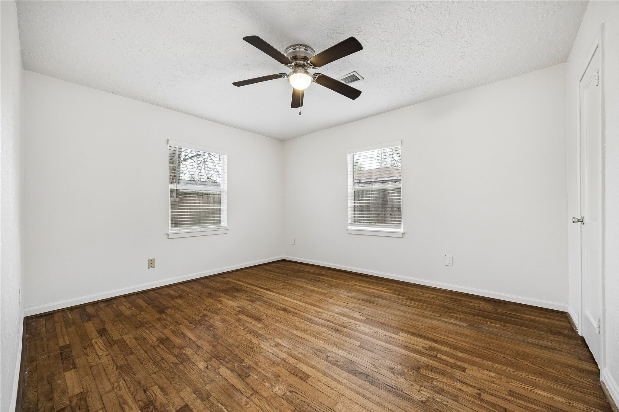 7515 Magnolia Street Houston, TX 77023 - Photo 10 of 16 The spacious 13×11 second bedroom features hardwood flooring, two large windows that bring in abundant natural light, a walk-in closet, and a ceiling fan with light—creating a bright and comfortable space.
