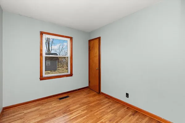 a view of an empty room with window and wooden floor