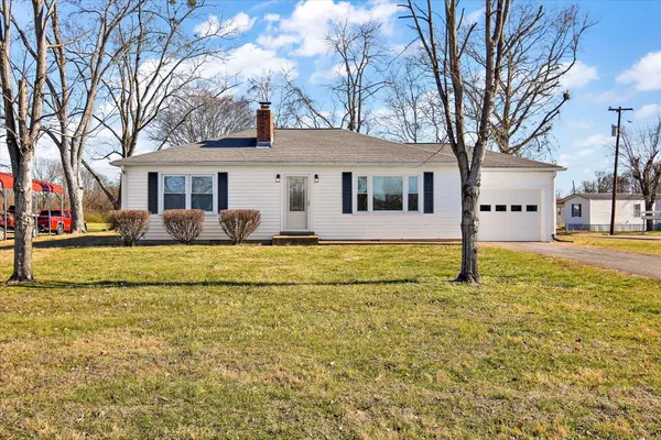 a front view of house with yard and trees around