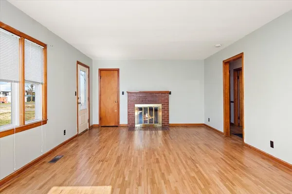 a view of an empty room with glass door and wooden floor