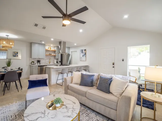 a living room with furniture kitchen view and a chandelier