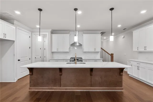 a kitchen with kitchen island stainless steel appliances a dining table chairs sink and wooden floor