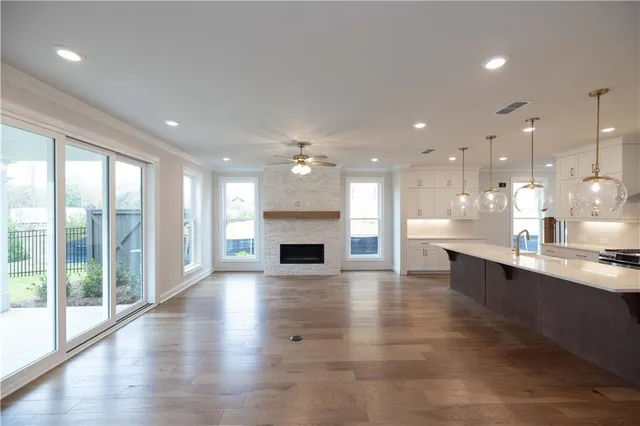 a large kitchen with granite countertop a large counter top a chandelier stainless steel appliances and windows