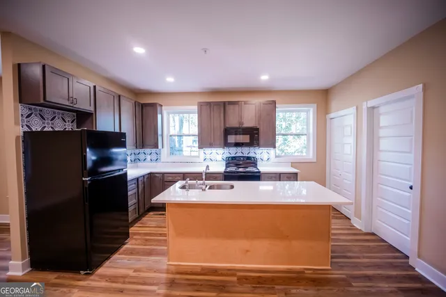 a kitchen with stainless steel appliances granite countertop a refrigerator a sink dishwasher a stove top oven a refrigerator with wooden cabinets and wooden floor