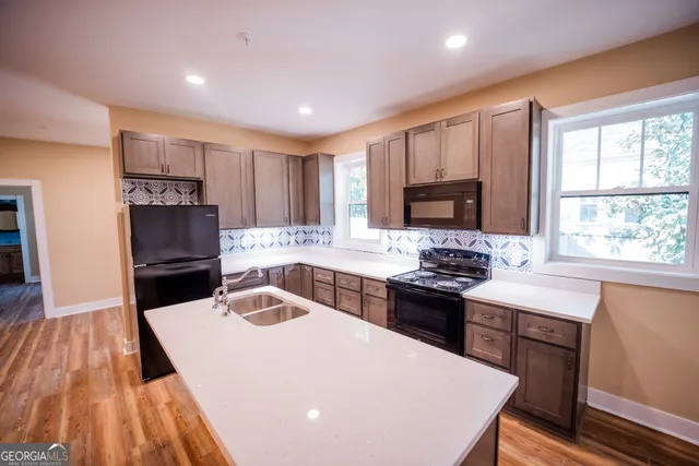 a large kitchen with stainless steel appliances a large counter top a stove and a wooden floors