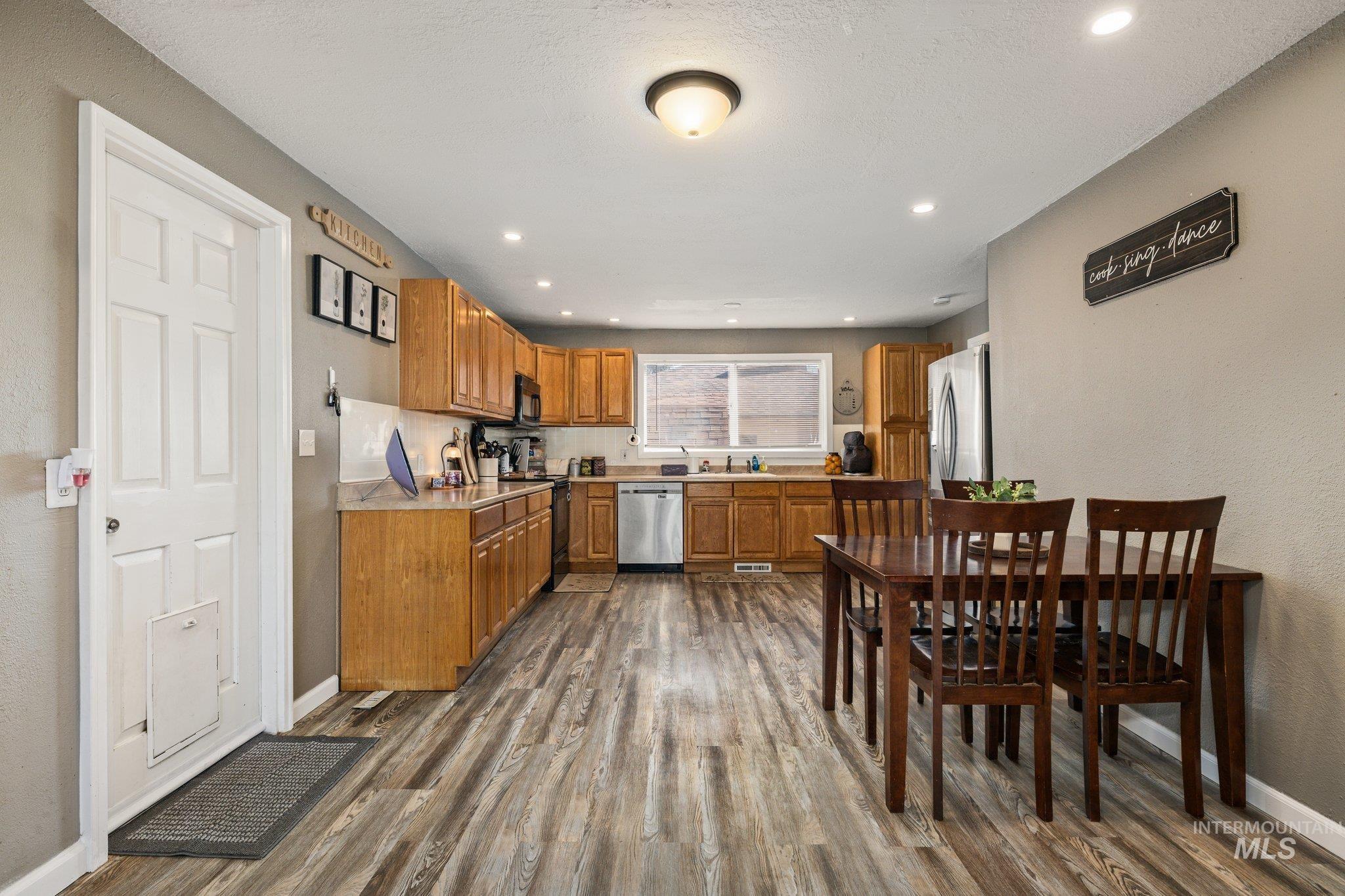 1504 2nd Street North Nampa, ID 83687 - Photo 8 of 29 Kitchen with wood finish cabinetry, light countertops, black appliances, dark wood-style flooring, and a textured wall