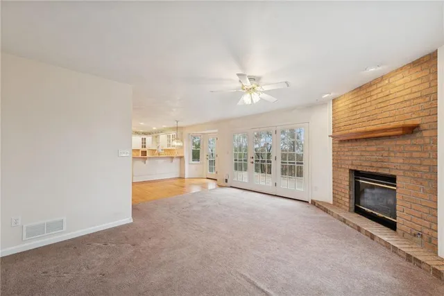 an empty room with windows fireplace and a ceiling fan