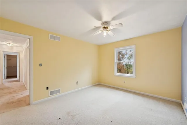 a view of an empty room with chandelier fan and wooden floor