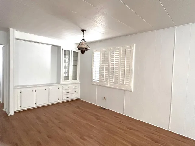 an empty room with wooden floor cabinet and windows