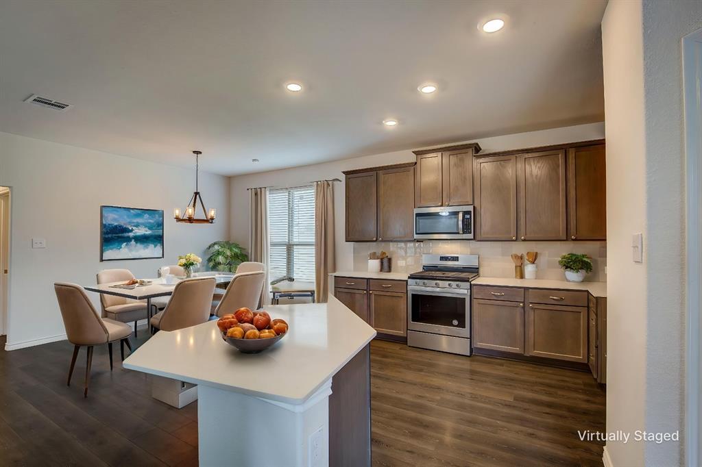 2703 Sayers Way Forney, TX 75126 - Photo 4 of 23 a kitchen with stainless steel appliances kitchen island granite countertop a stove a sink a refrigerator and white cabinets with wooden floor