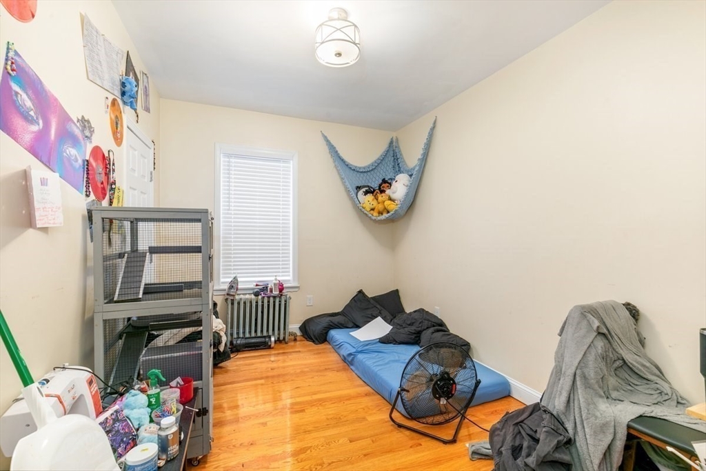 187 Highland Street Boston, MA 02119 - Photo 15 of 21 a bedroom with a bed and a chandelier