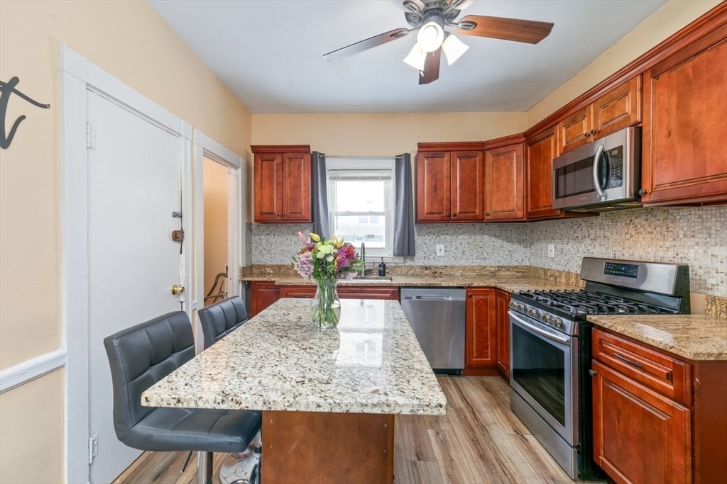 187 Highland Street Boston, MA 02119 - Photo 3 of 21 a kitchen with stainless steel appliances granite countertop a stove top oven a sink dishwasher and cabinets with wooden floor