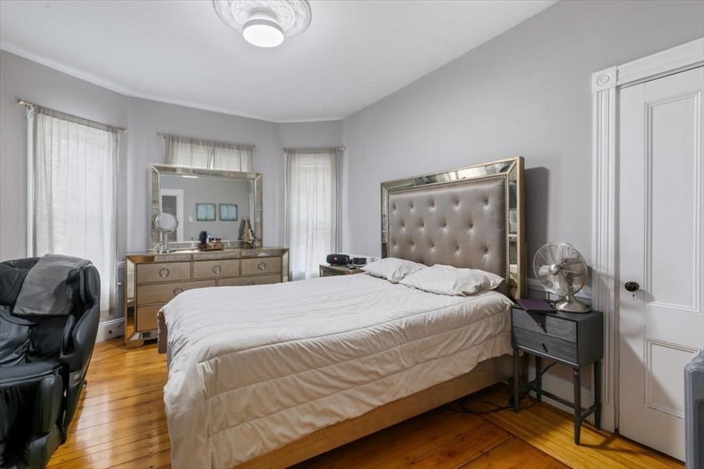 187 Highland Street Boston, MA 02119 - Photo 7 of 21 a bedroom with a bed and wooden floor