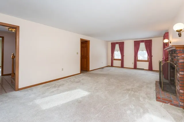 an empty room with windows and fireplace