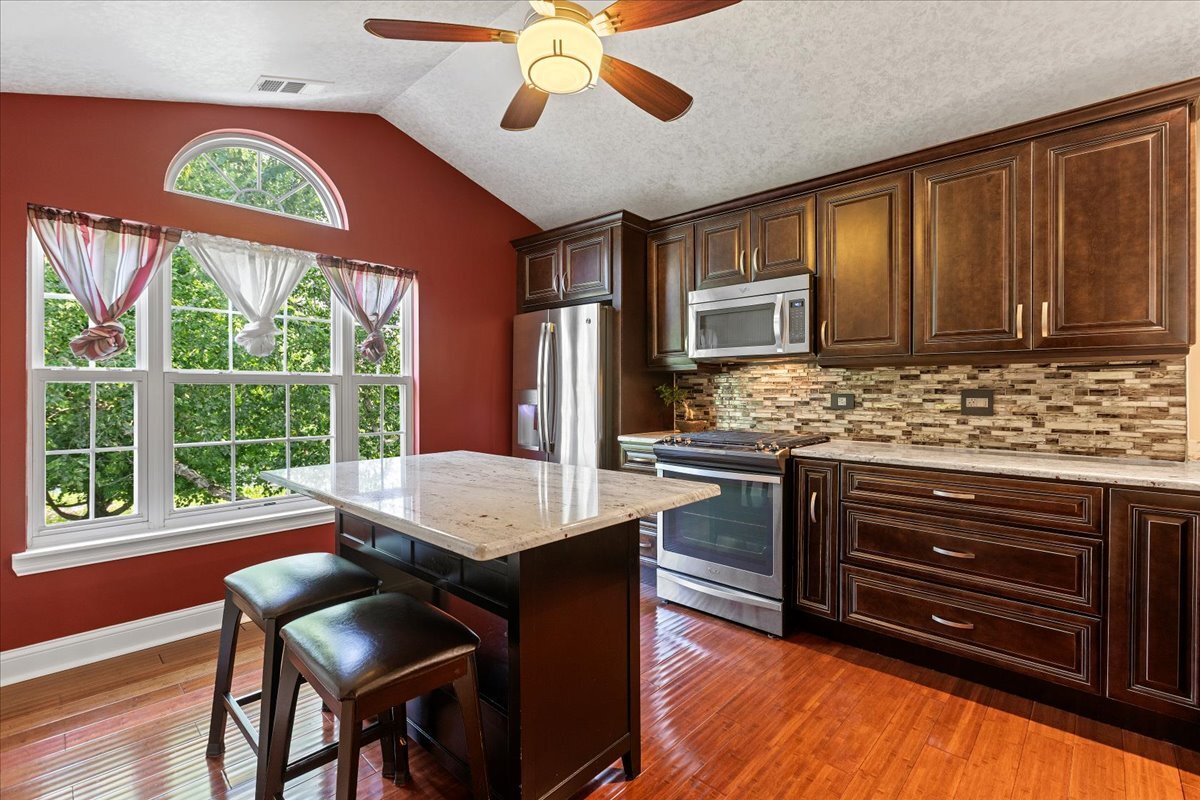 1636 Columbia Circle, Unit 2 Bartlett, IL 60103 - Photo 6 of 47 a kitchen with stainless steel appliances granite countertop wooden cabinets a stove a sink a dining table and chairs with wooden floor