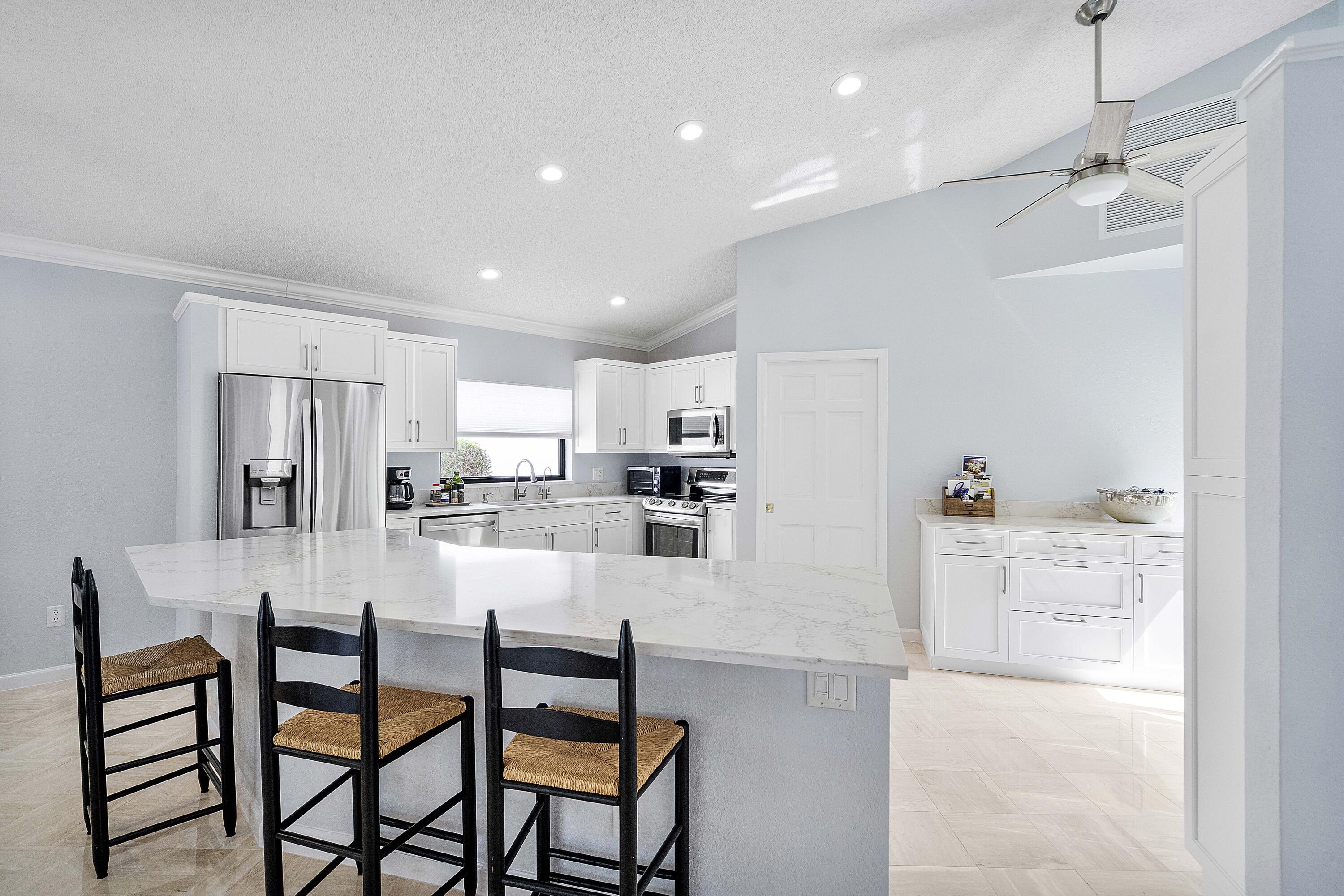 22652 Esplanada Circle Boca Raton, FL 33433 - Photo 33 of 44 a kitchen with kitchen island wooden cabinets and refrigerator