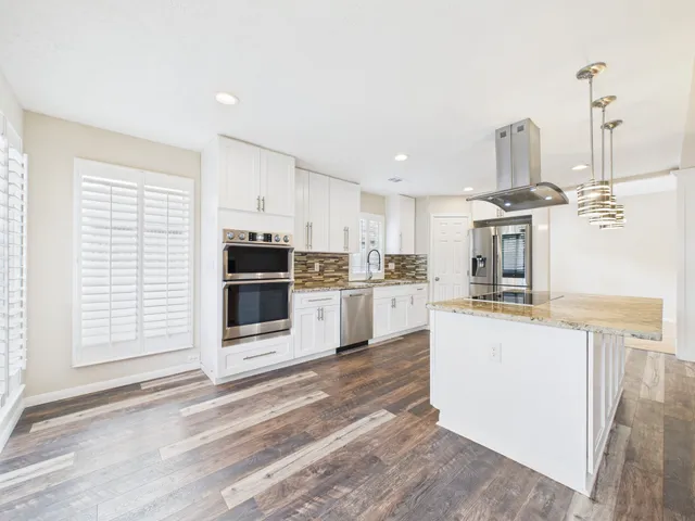 a kitchen with stainless steel appliances granite countertop a stove and a wooden floors