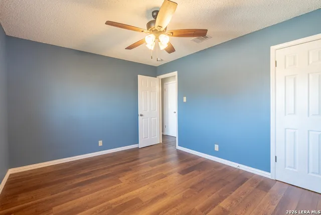 an empty room with wooden floor and fan
