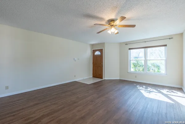 an empty room with wooden floor fan and windows