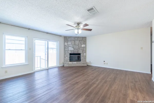 an empty room with wooden floor ceiling fan and windows