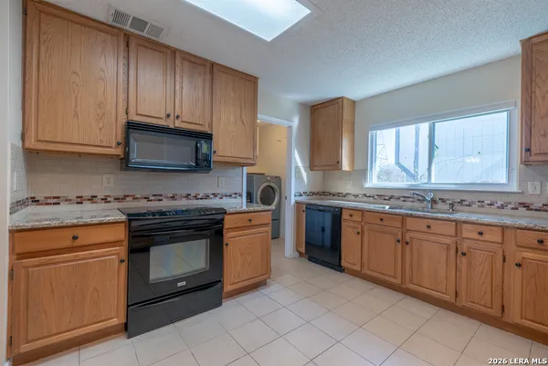 a kitchen with stainless steel appliances granite countertop a stove a sink and a microwave