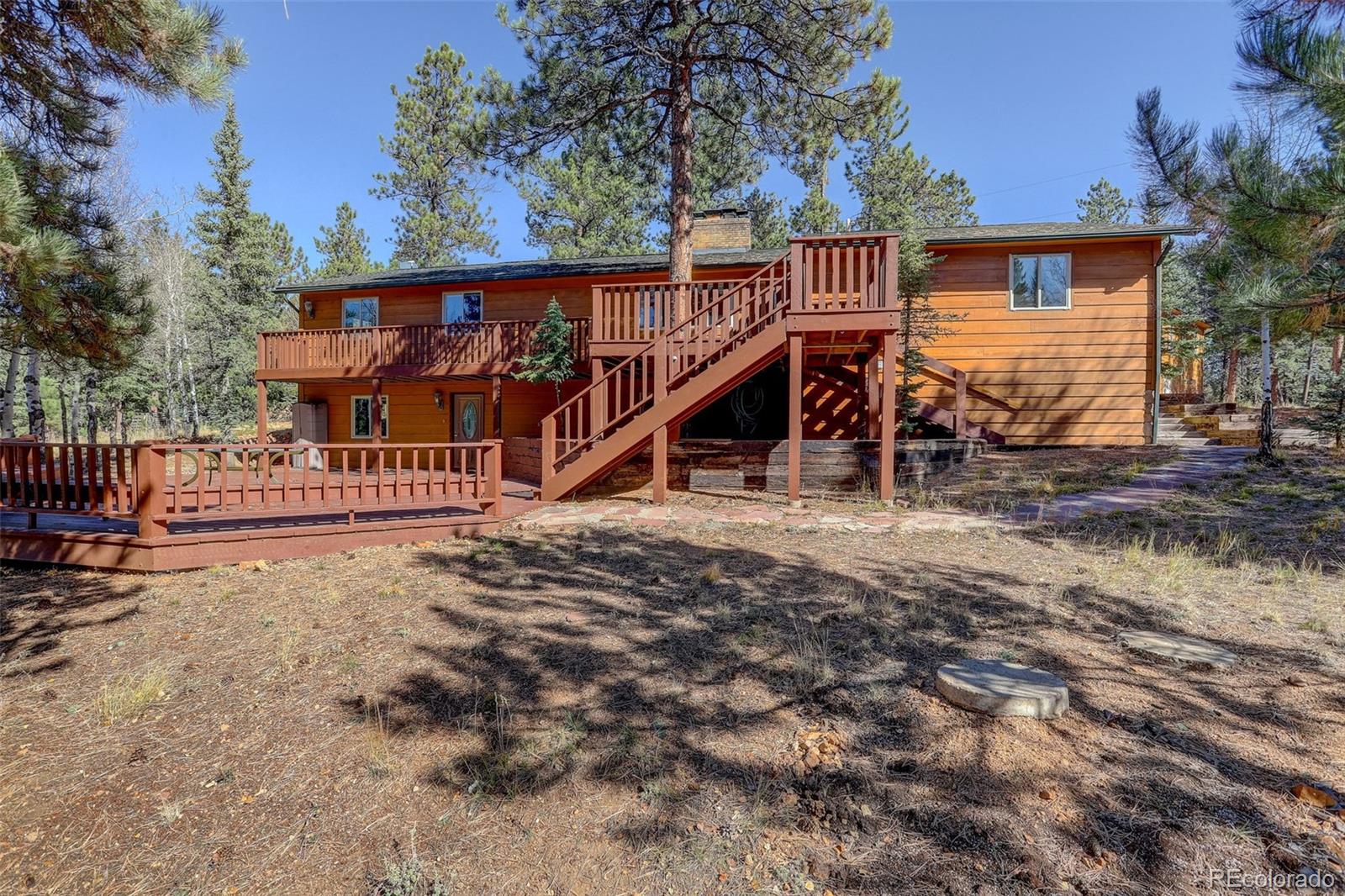 225 Spring Drive Pine, CO 80470 - Photo 5 of 44 a view of a house with wooden deck and a backyard
