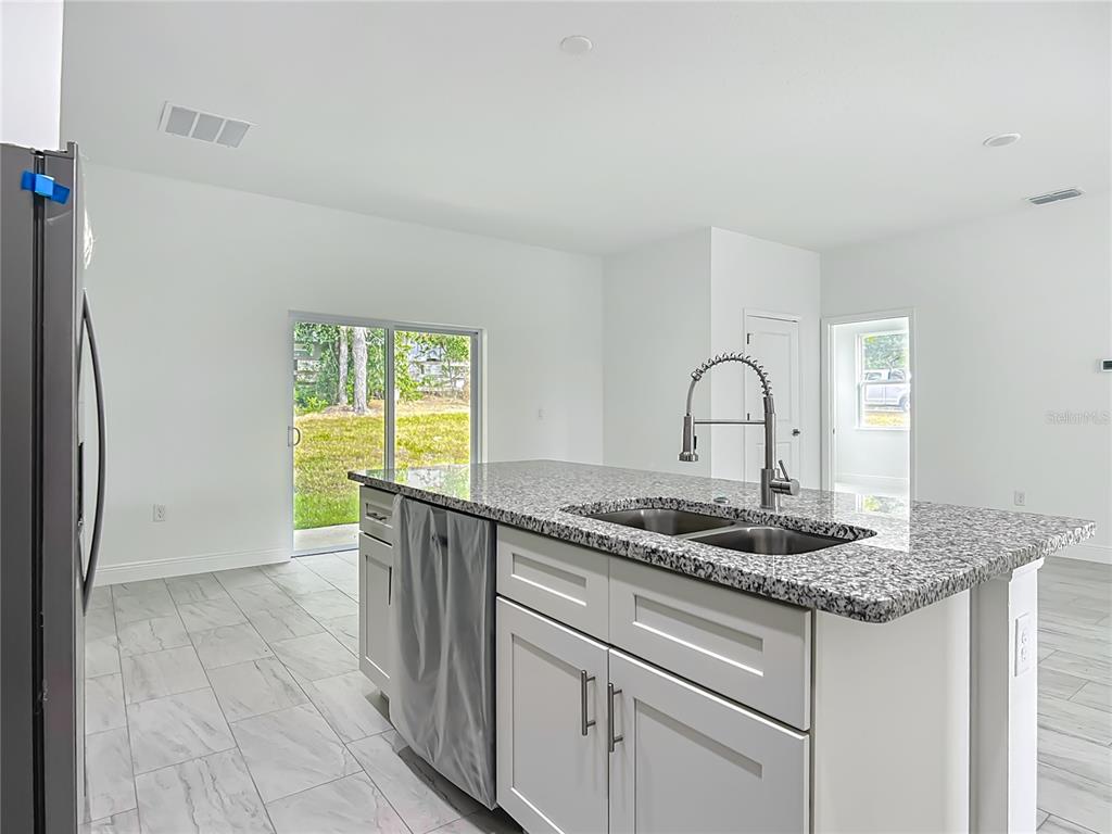 5736 North Claremont Drive Citrus Springs, FL 34434 - Photo 14 of 45 a kitchen with granite countertop a sink white cabinets and a window