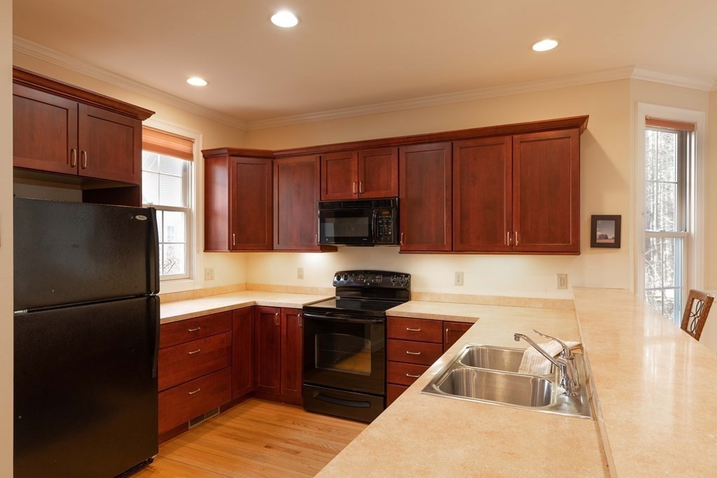359 Main Street, Unit 15A Easthampton, MA 01027 - Photo 5 of 24 a kitchen with granite countertop wooden cabinets a refrigerator and a sink