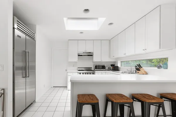 a kitchen with stainless steel appliances granite countertop a refrigerator a sink a stove and white cabinets