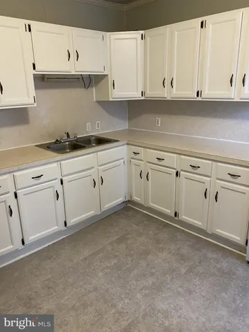 a kitchen with granite countertop white cabinets and a sink