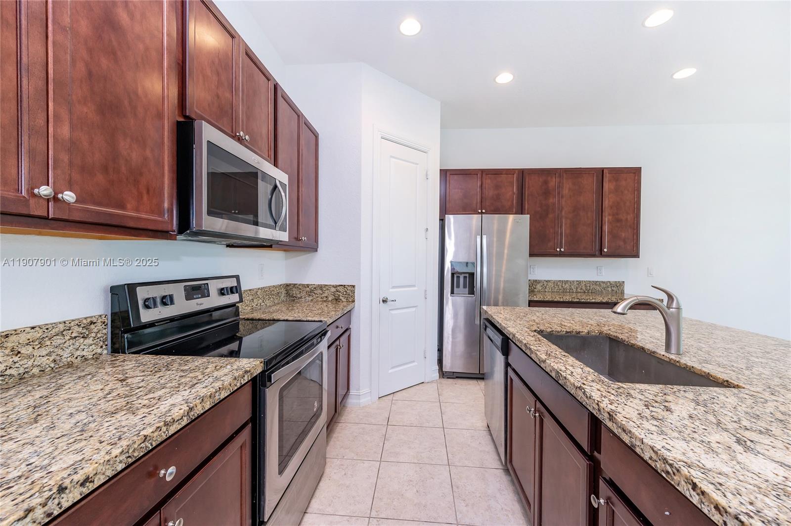 11670 Southwest 13th Lane, Unit 11670 Pembroke Pines, FL 33025 - Photo 20 of 38 a kitchen with stainless steel appliances granite countertop a sink stove microwave and refrigerator