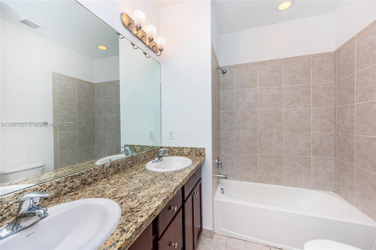11670 Southwest 13th Lane, Unit 11670 Pembroke Pines, FL 33025 - Photo 22 of 38 a bathroom with a granite countertop tub sink and mirror