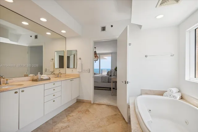a bathroom with a tub a sink double vanity and mirrors