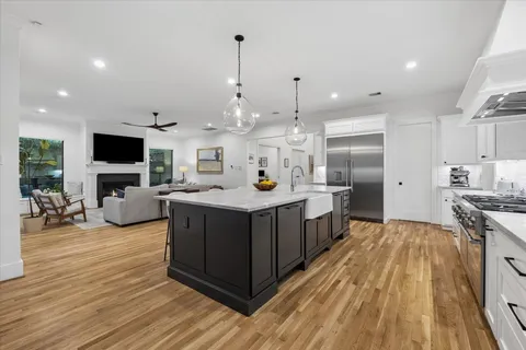 a kitchen with stainless steel appliances a stove top oven a sink dishwasher and a refrigerator with wooden floor