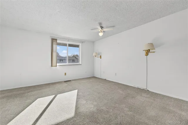 an empty room with windows and ceiling fan