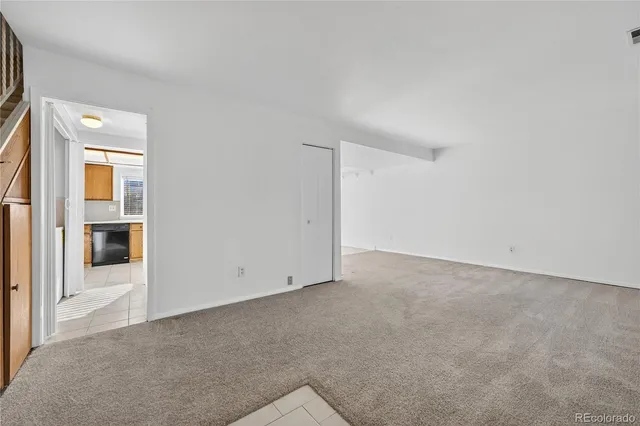 an empty room with an entryway and kitchen view