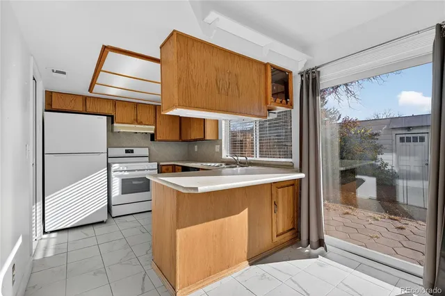 a kitchen with a stove a refrigerator and a view of living room