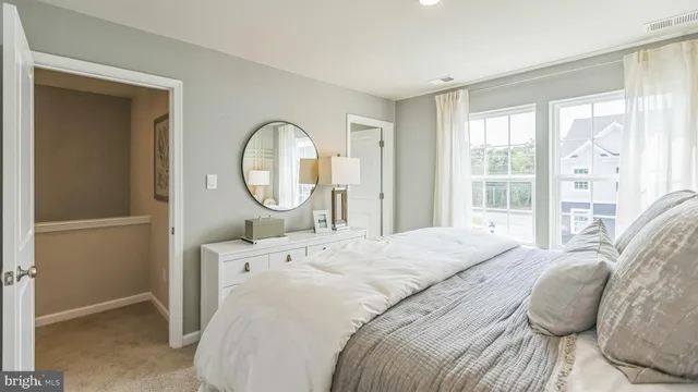 a bedroom with a bed a mirror and a large window
