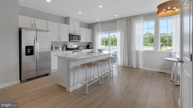 a kitchen with stainless steel appliances granite countertop a refrigerator a sink dishwasher a stove and a refrigerator with wooden floor