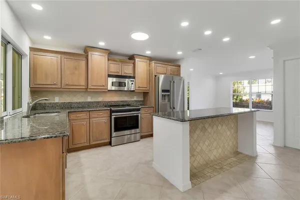 a kitchen with stainless steel appliances granite countertop a stove a sink and a refrigerator