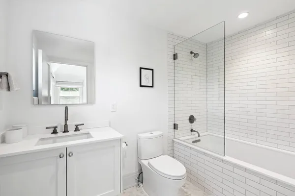 a bathroom with a toilet a sink a mirror a shower and vanity