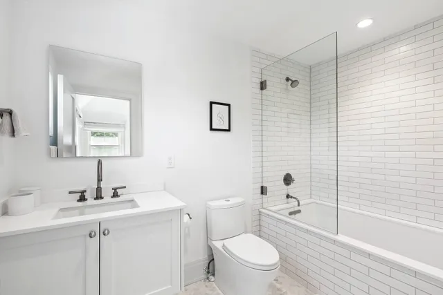 a bathroom with a toilet a sink a mirror a shower and vanity