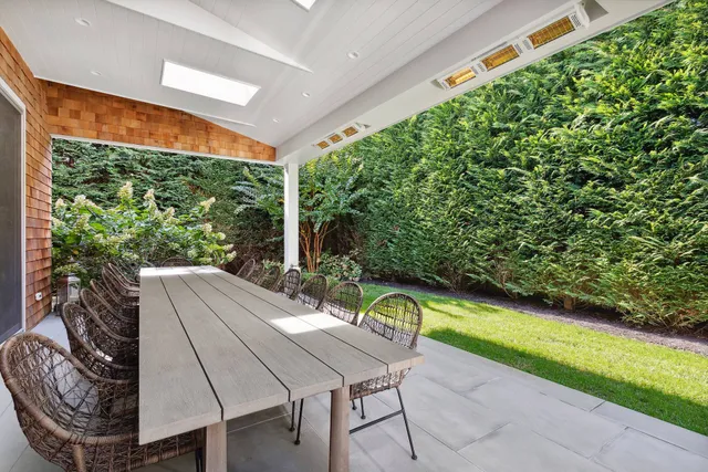 a view of a patio with table and chairs potted plants with floor to ceiling window and tree